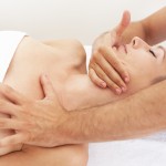 Physiotherapist massaging tight neck muscles and gently stretching to relieve pain