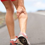 A man stopping to feel his painful calf while out running